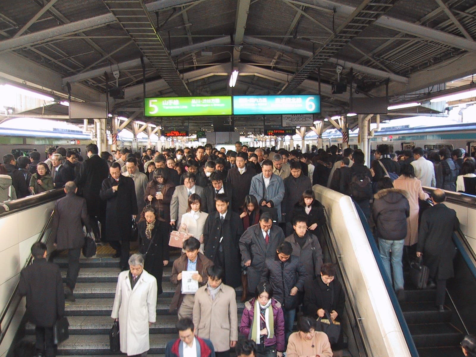 Foule dense de navetteurs pressés sur un quai de gare de Tokyo aux heures de pointe, illustrant la pression du surtravail au Japon.