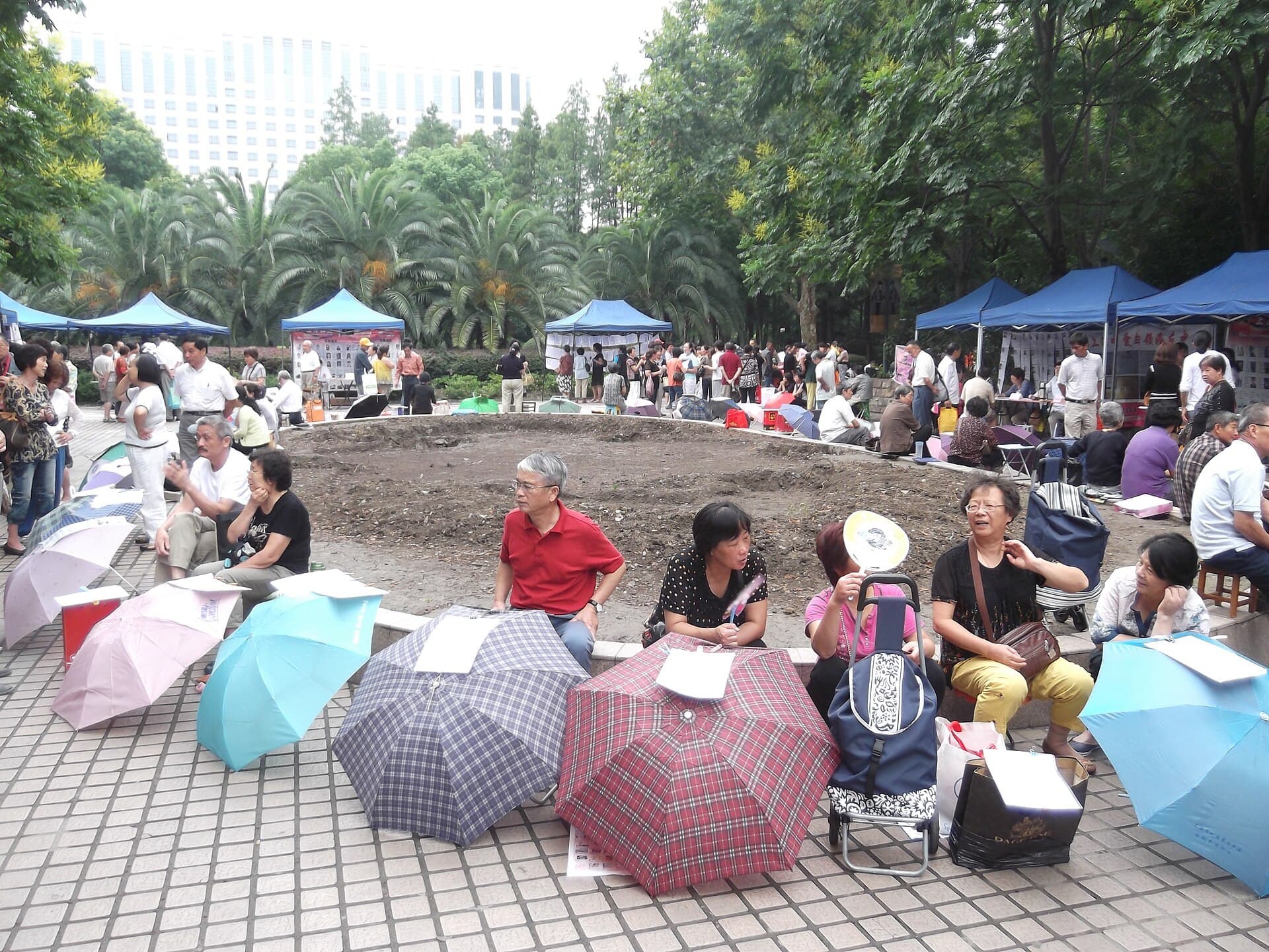 Des parapluies ouverts couverts de fiches de célibataires alignés dans une allée du marché du mariage au Parc du Peuple de Shanghai, avec des stands en arrière-plan.