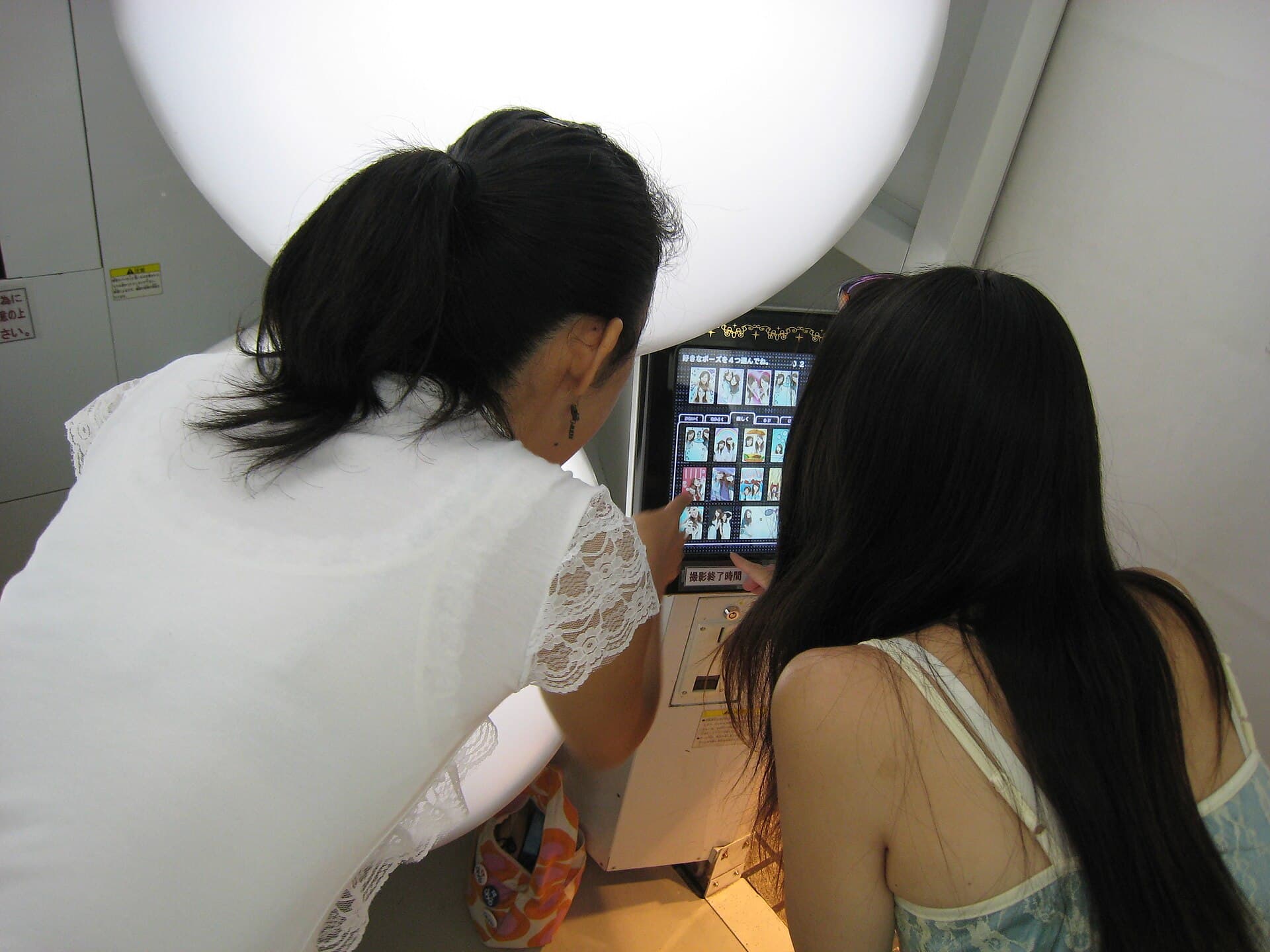Rangée de cabines de purikura aux façades roses et colorées dans une salle d'arcade d'Osaka au Japon