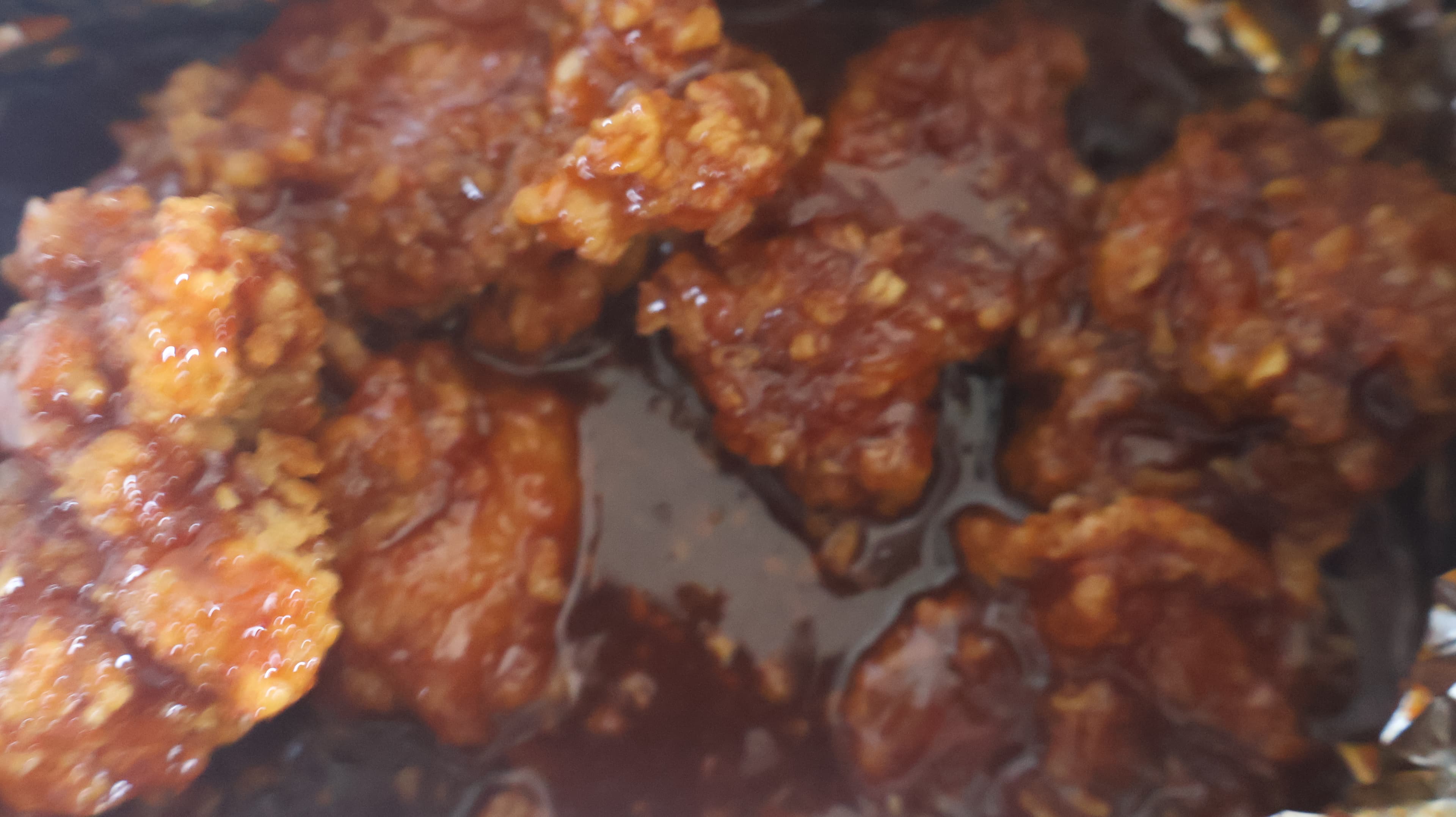 Assiette de poulet frit coréen yangnyeom nappée de sauce rouge sucrée-épicée, plat vedette du chimaek.