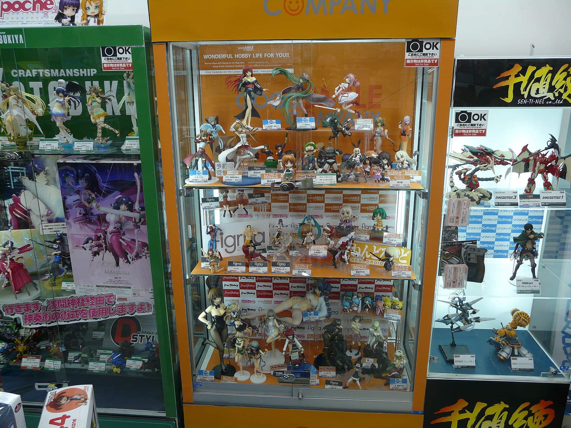 Vitrine d'une boutique d'Akihabara a Tokyo remplie de figurines japonaises : pieces a l'echelle, figma articulees et Nendoroid alignees sur trois etageres avec leurs etiquettes de prix