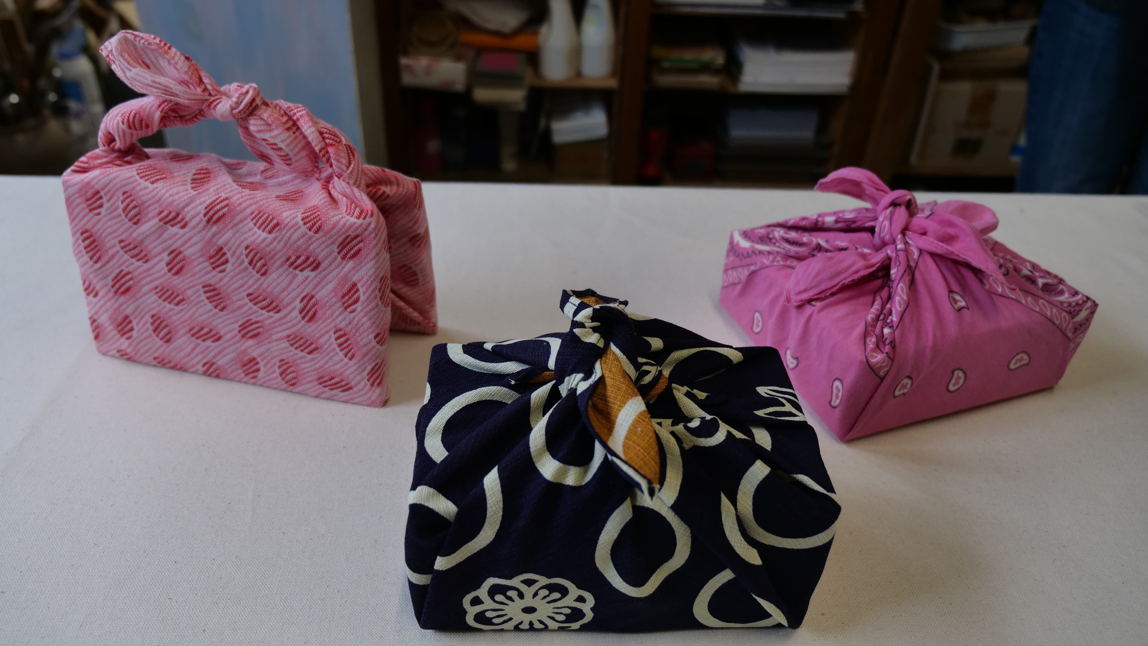 Technique traditionnelle japonaise du furoshiki : un objet emballé et noué dans un tissu décoratif.