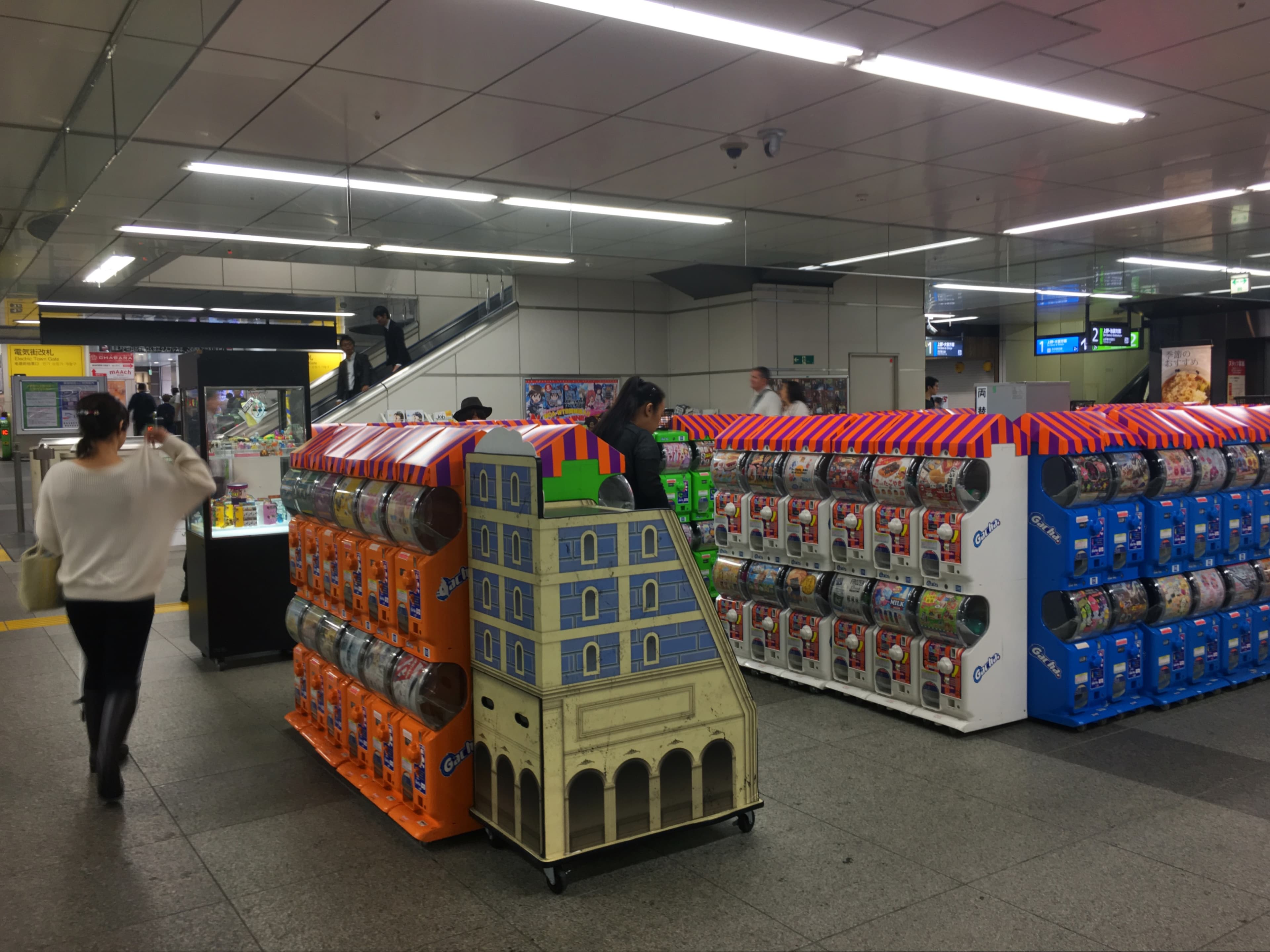 Mur de distributeurs de gachapon colorés alignés dans une gare d'Akihabara à Tōkyō.