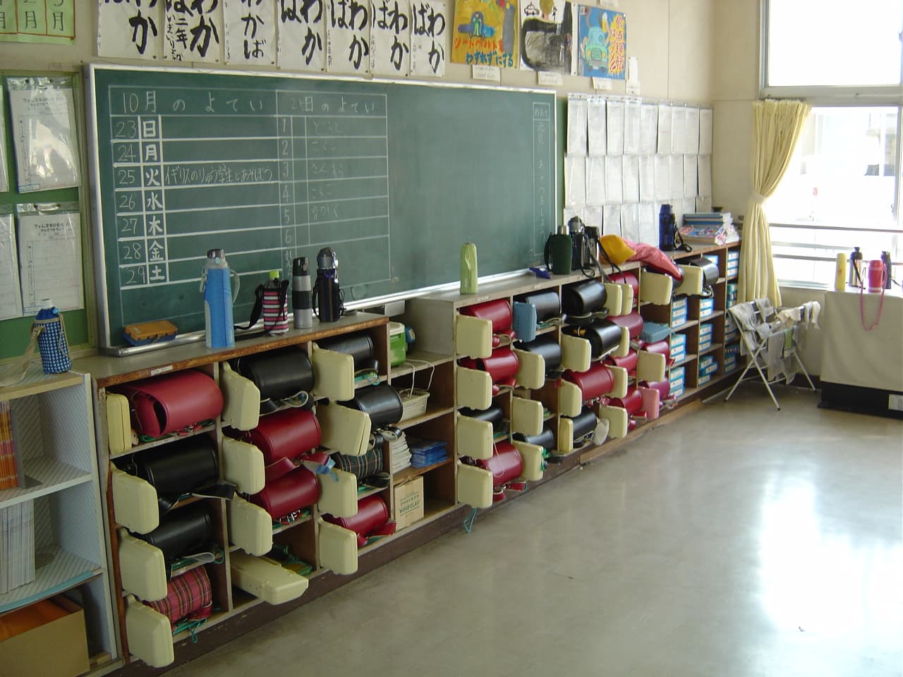 Salle de classe typique d'une école élémentaire japonaise, avec cartables et casiers au fond.