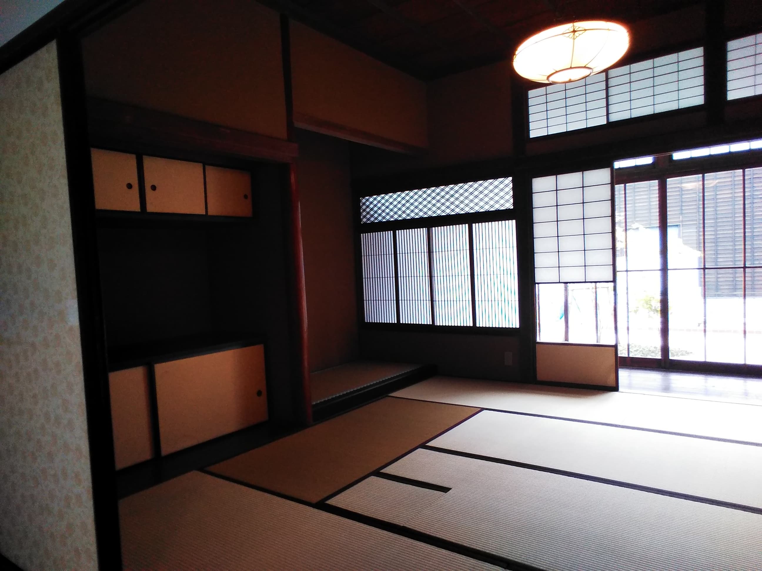 Pièce japonaise traditionnelle en tatamis presque vide, baignée de lumière à travers un shōji, illustrant l'esthétique du vide.