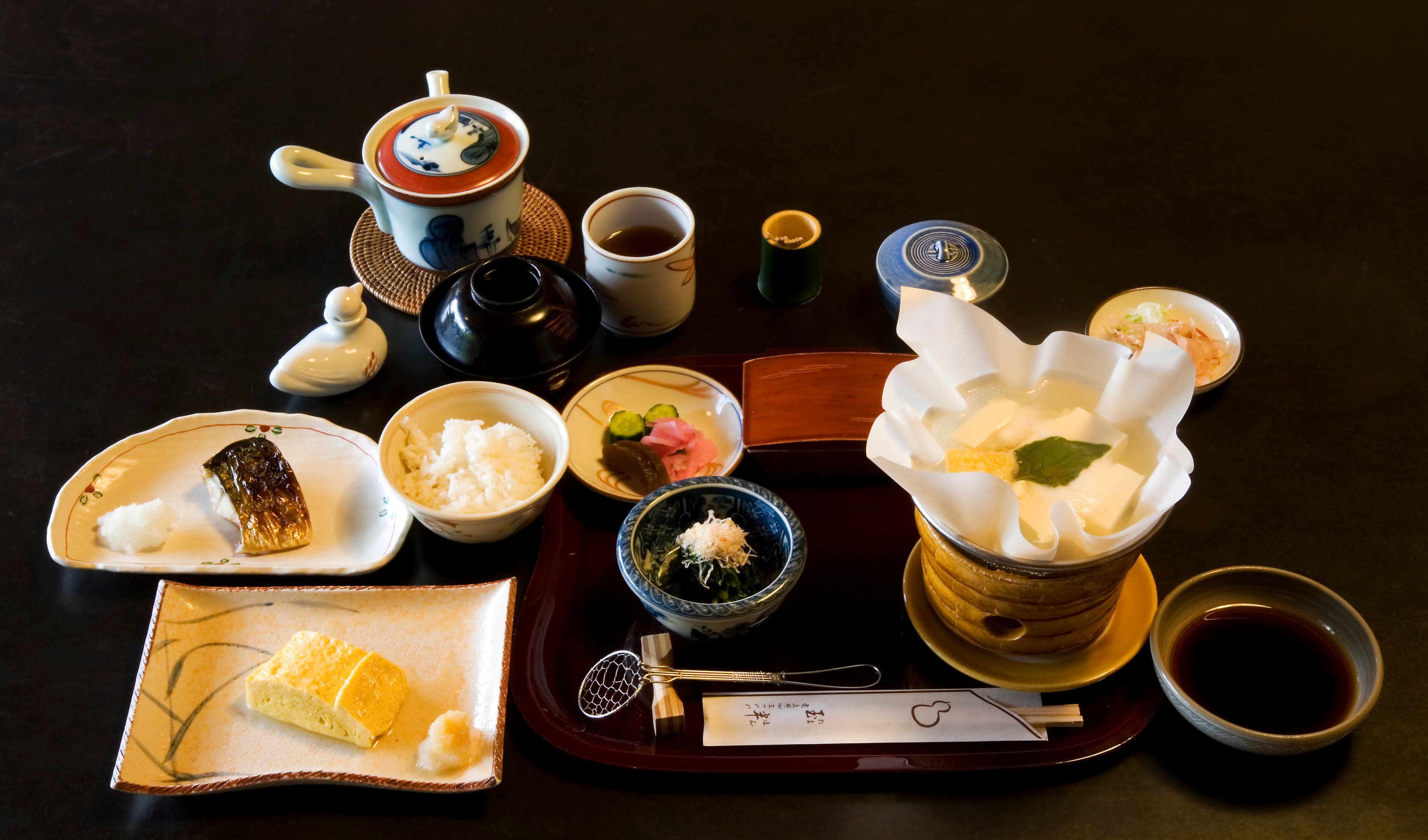 Petit-déjeuner japonais traditionnel servi sur un plateau dans un ryokan de Kyoto, avec riz, soupe miso, poisson grillé et petits accompagnements