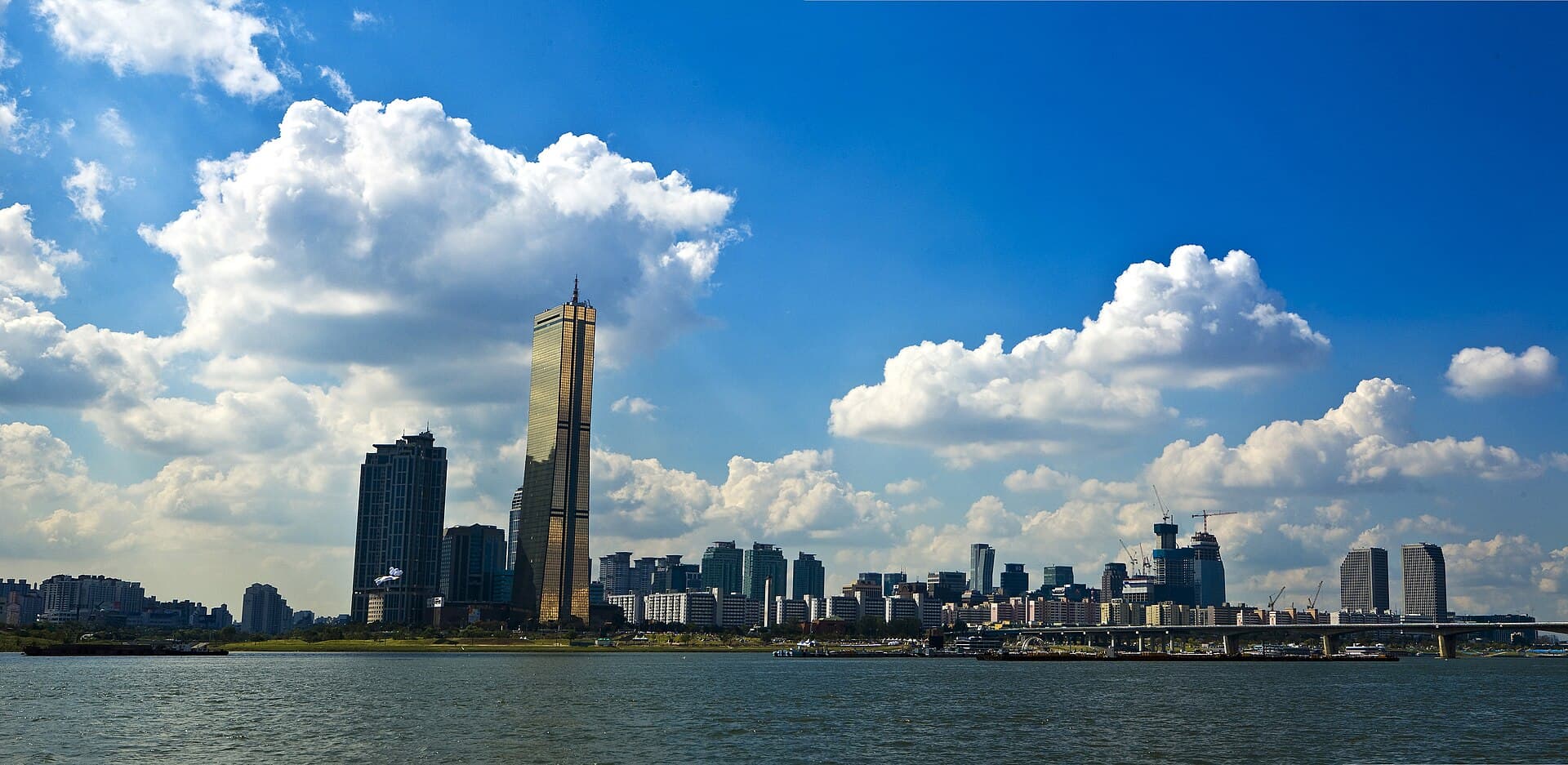 Le fleuve Han a Seoul, avec la ligne d'horizon de l'ile de Yeouido et sa tour doree sous un ciel de cumulus